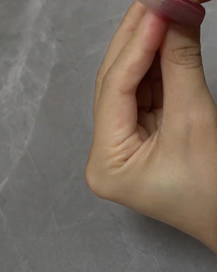 A brush applying cat eye gel evenly over the nail surface.