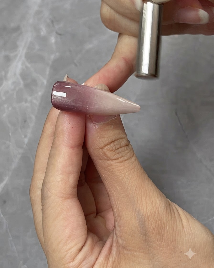 A cylindrical magnet held closely above a cat-eye gel nail tip to shape the magnetic light reflection.