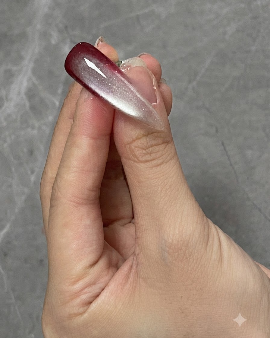 A finger with a cured gradient and cat eye nail design positioned under a curing lamp.