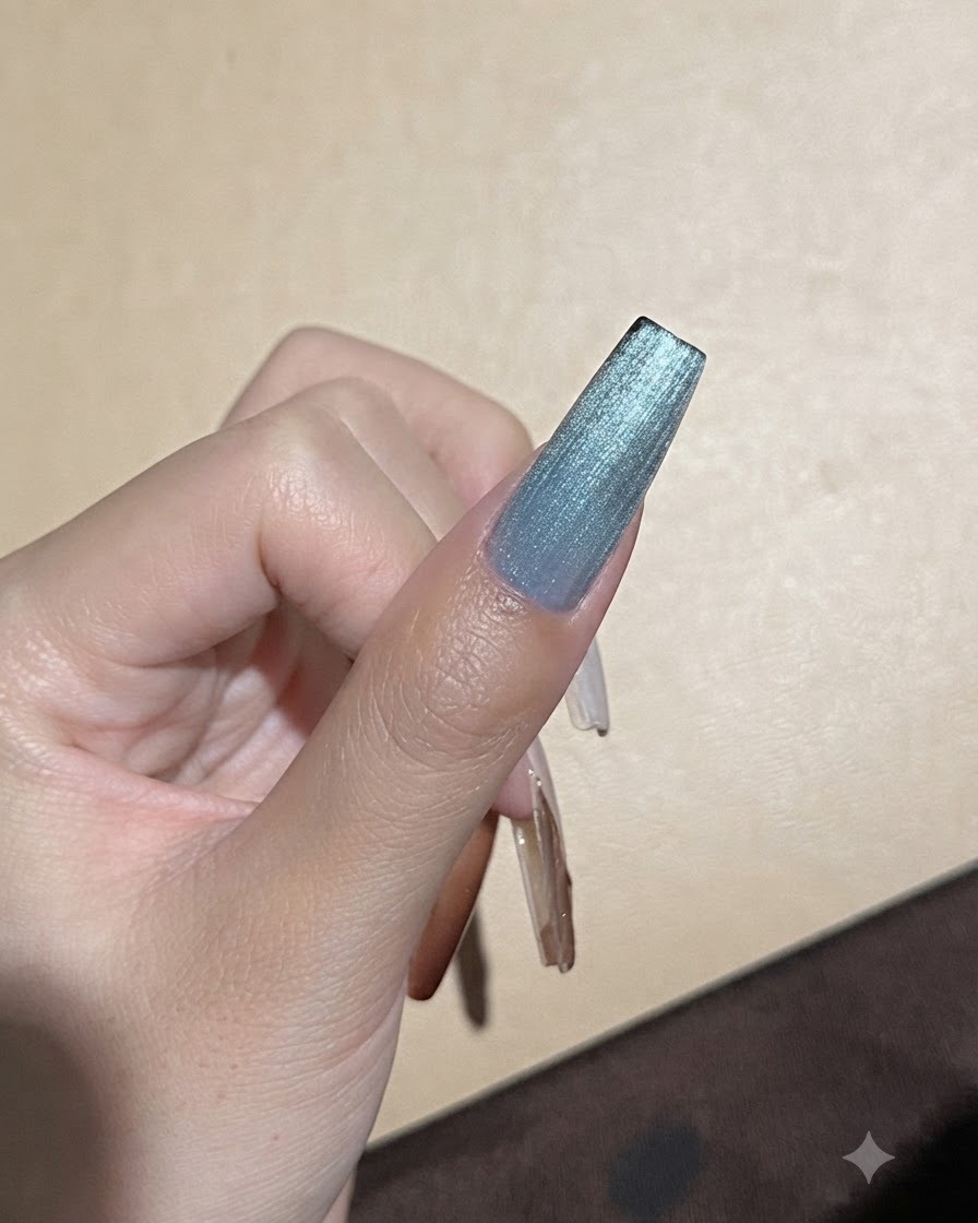 A strong magnet held close to a blue cat-eye gel nail to refine the light reflection line.