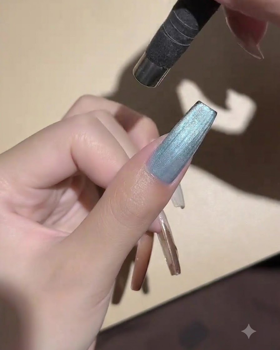A handheld mini UV LED lamp positioned directly above a painted nail to cure the cat-eye gel.