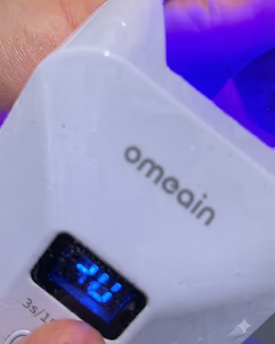 A small LED lamp illuminating a single finger during a brief spot-cure.