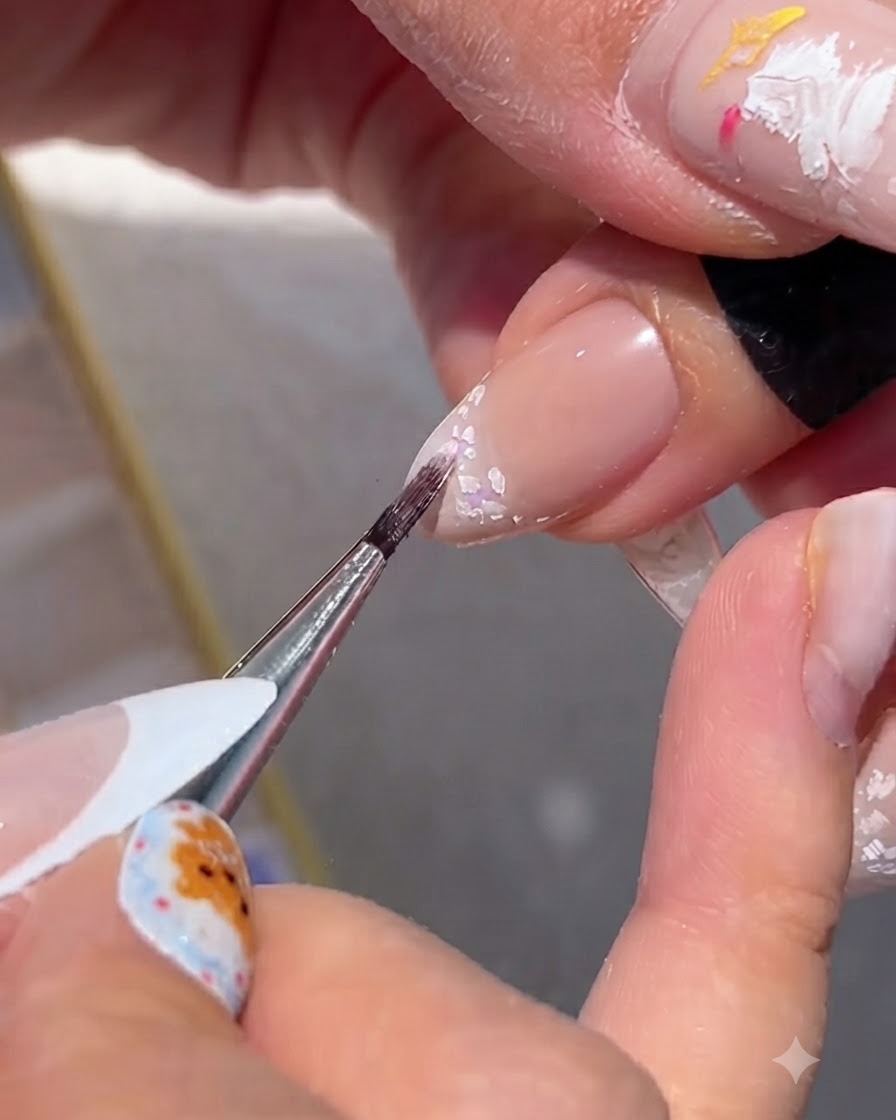 A fine brush blending soft color pigments into the white flower outlines.