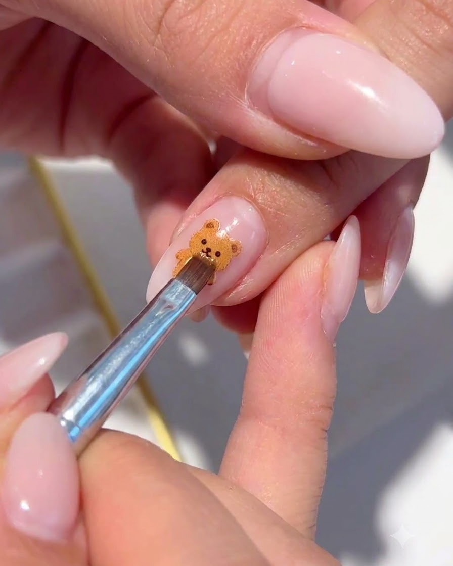 A fine brush placing iridescent shimmer flakes around the painted floral nail art.