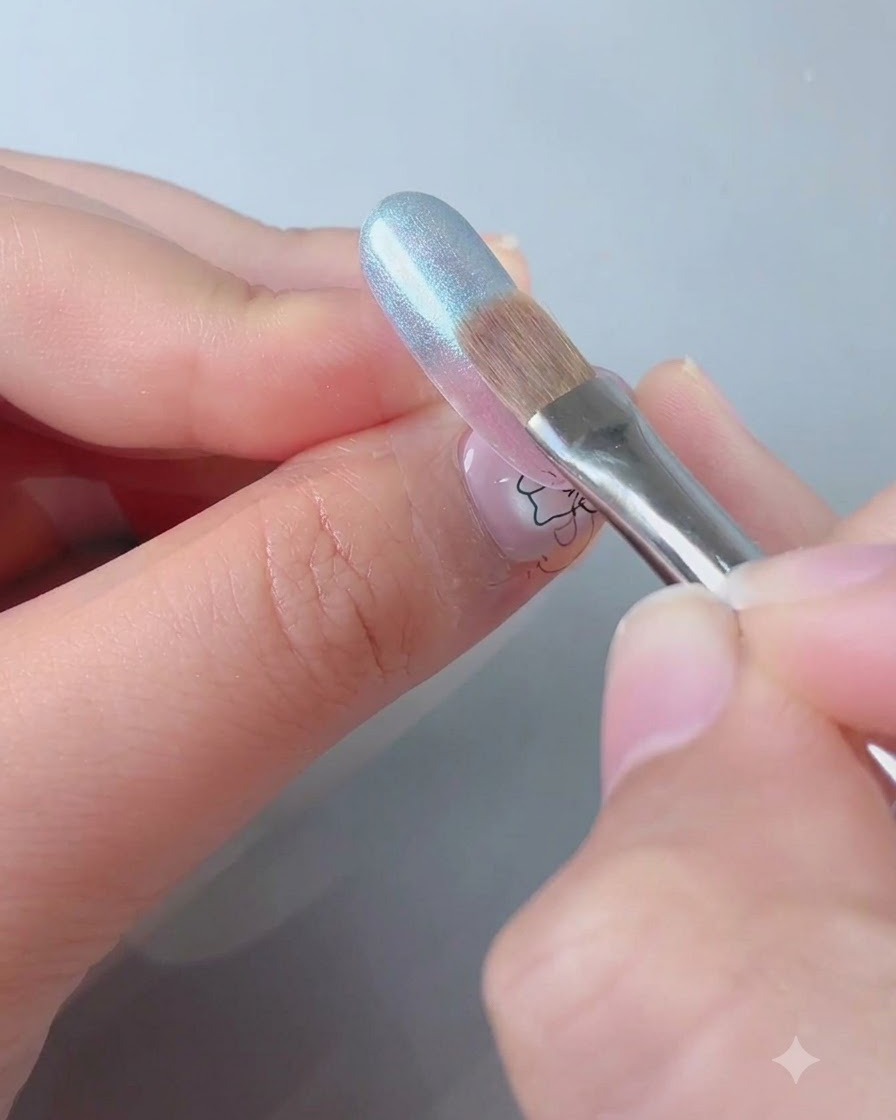 A swiping brush blending the blue shade downwards across the nail surface.