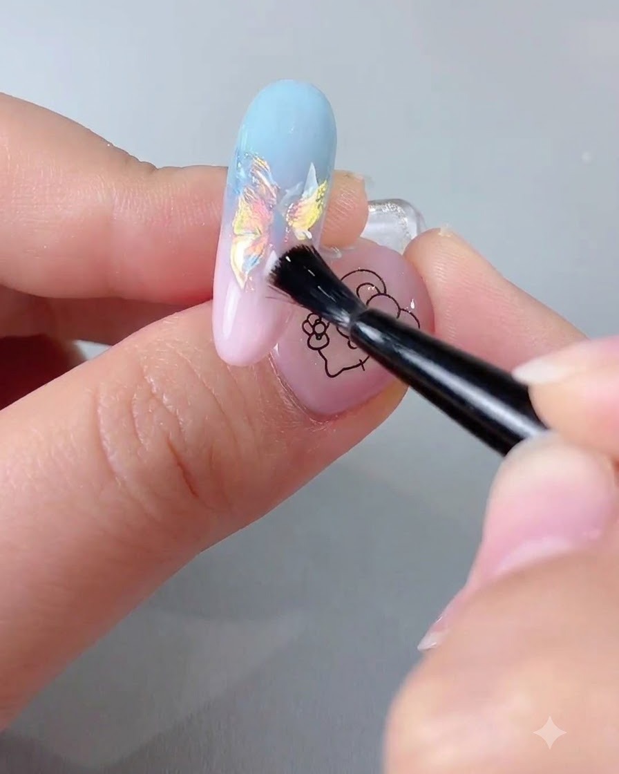 A nail brush applying a clear sealing top coat over an iridescent chrome-finished nail extension.