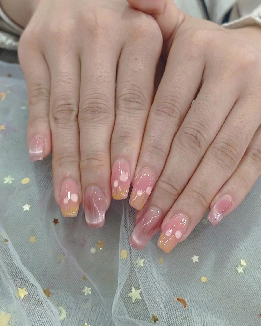 An ombre brush gently blending pink and yellow gel polish in the middle of the nail.