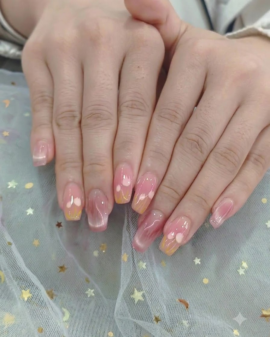 A brush sweeping a glossy top coat across a completed heart and gradient nail design.