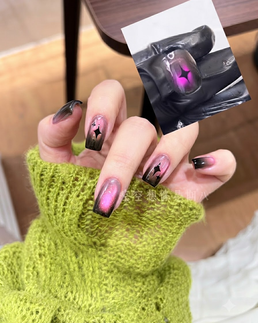 A metal cuticle pusher pressing down a black star nail decal onto a pink and black gradient nail.
