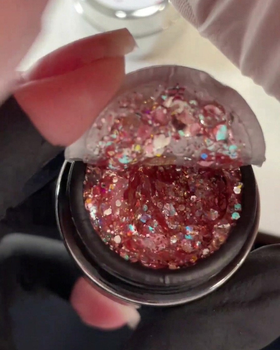 Open pot of thick gel packed with chunky pink, holographic, and duochrome glitter sequins.