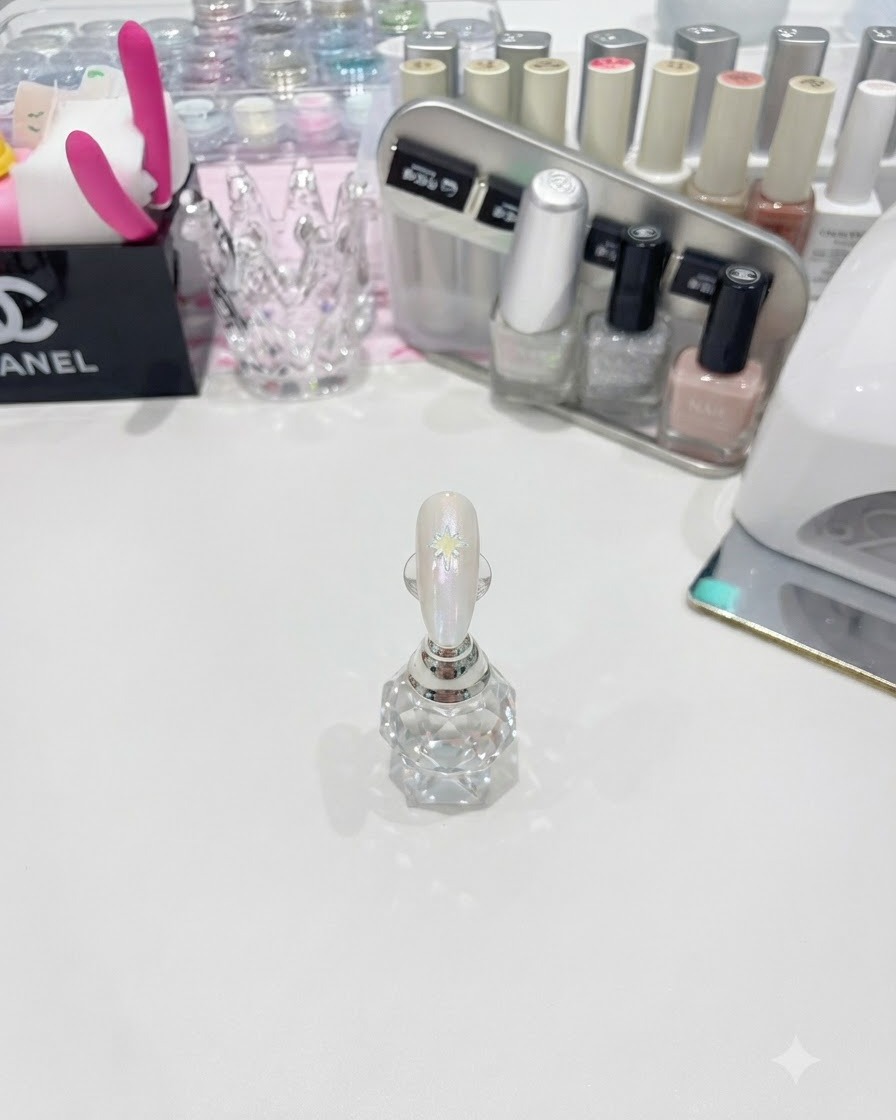 A fine liner brush drawing a white multi-pointed star on a glossy nail.