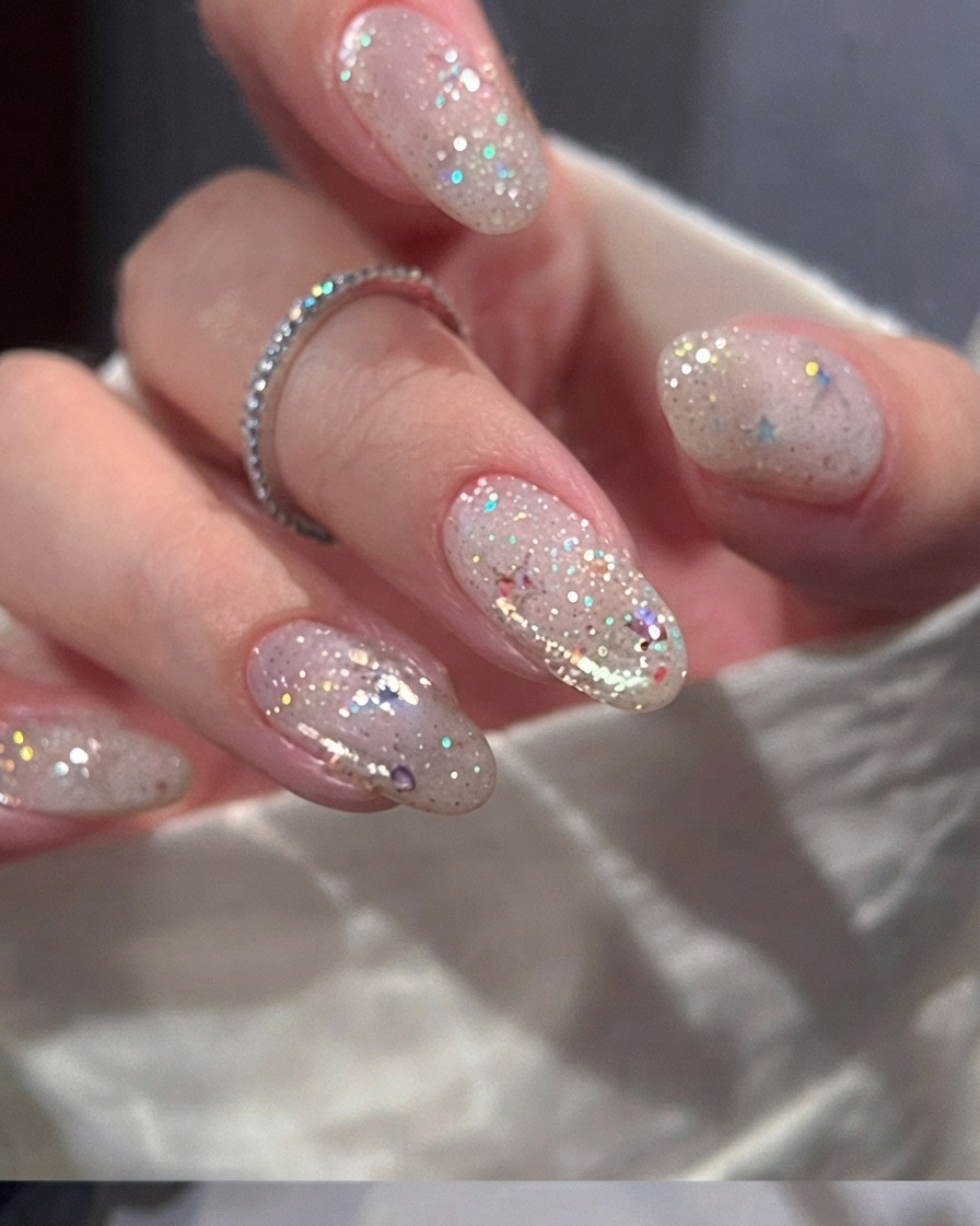 A nail brush applying a smooth coat of sheer nude pink gel polish onto a natural fingernail.