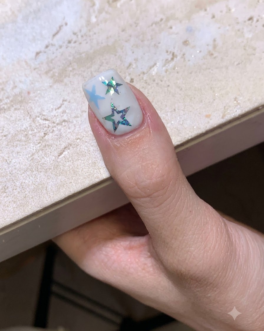 A completed star-themed manicure curing under a nail lamp.