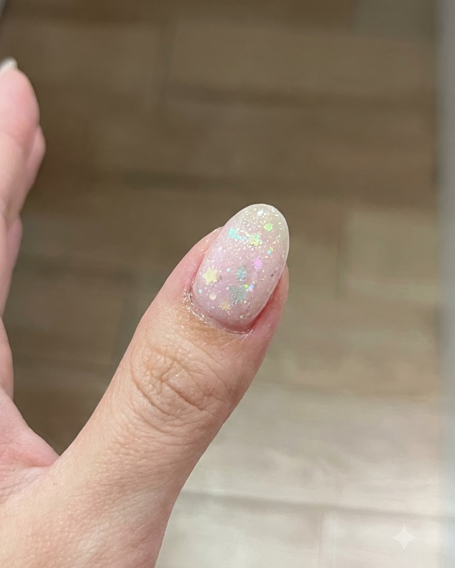 A brush applying a thin, clear coat of base gel onto the surface of a prepared fingernail.