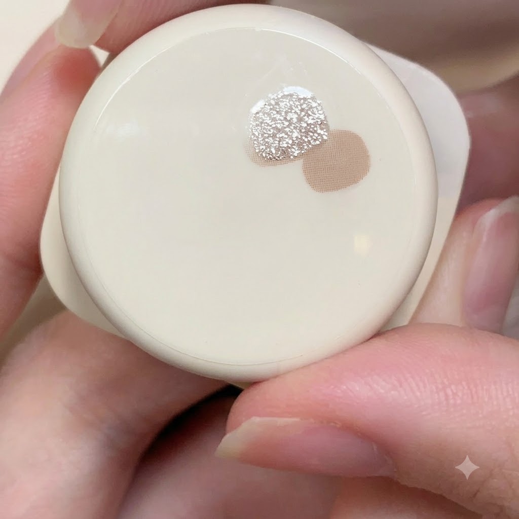 A close-up view of a small container holding fine light pink and silver reflective glitter gel next to another jar.