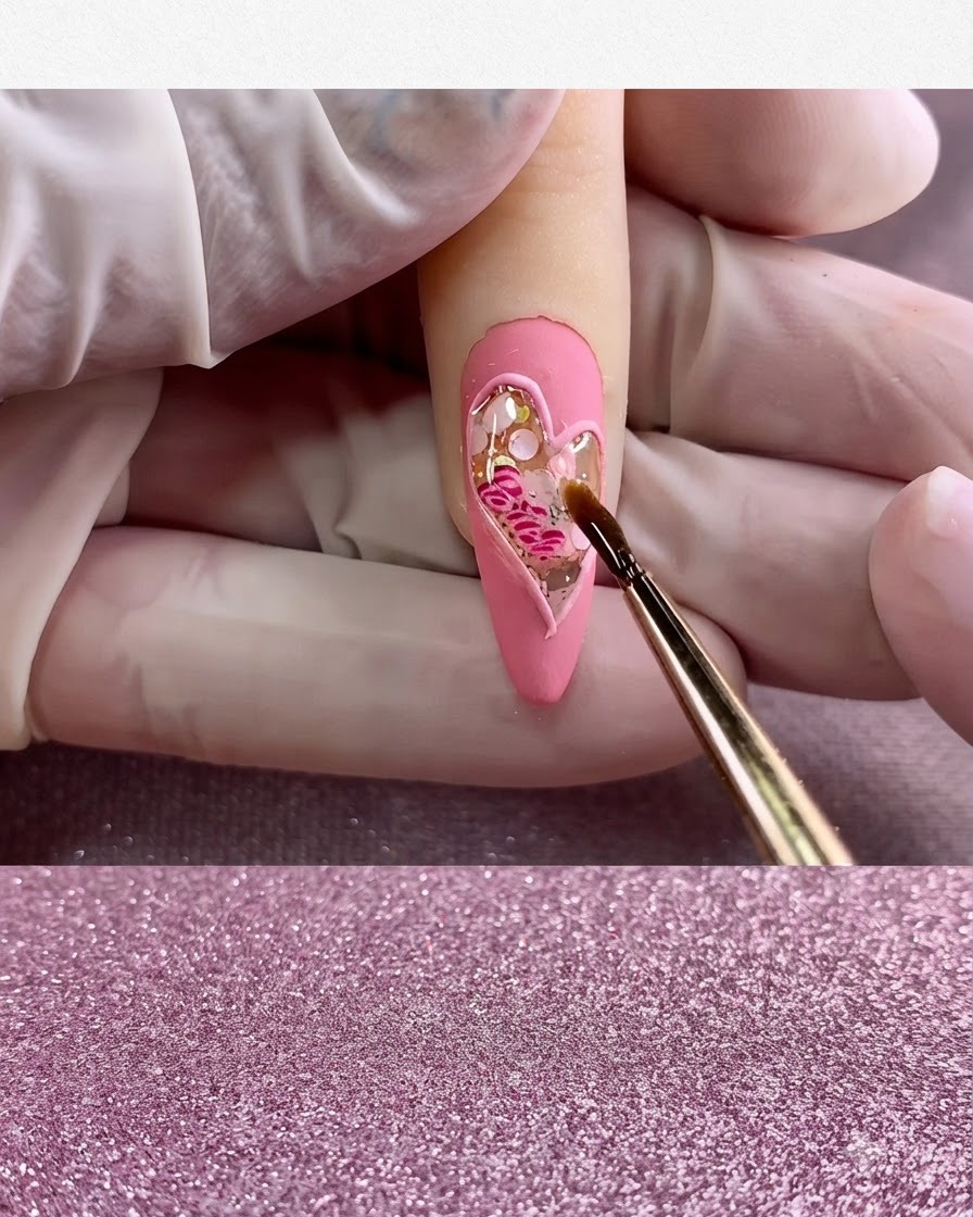 A fine brush applying clear glossy top coat exclusively inside the heart shape.