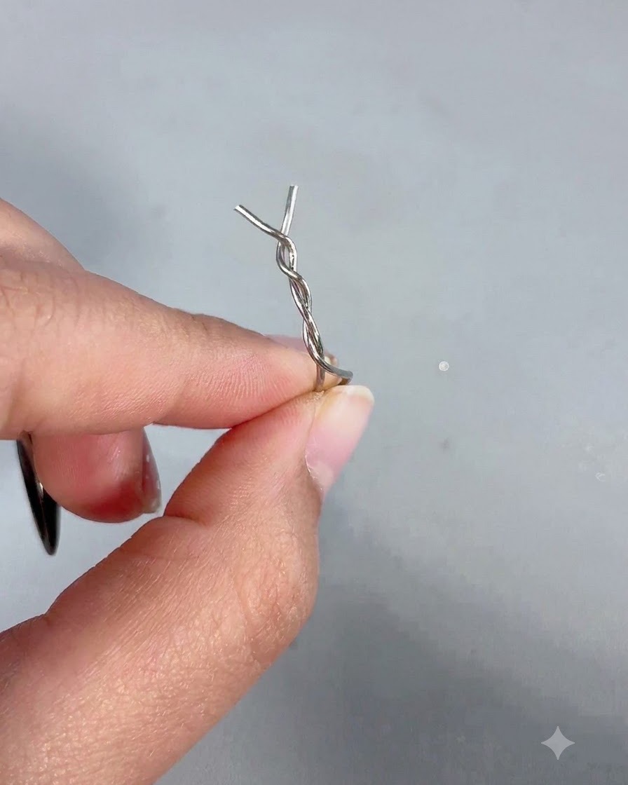 A hand holding a magnetic wand with a twisted metal hairpin attached to its tip.