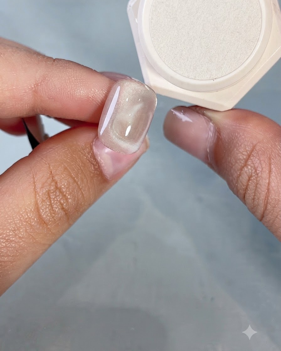 A close-up of a nail brush drawing a small heart outline on top of an existing cat-eye heart design.