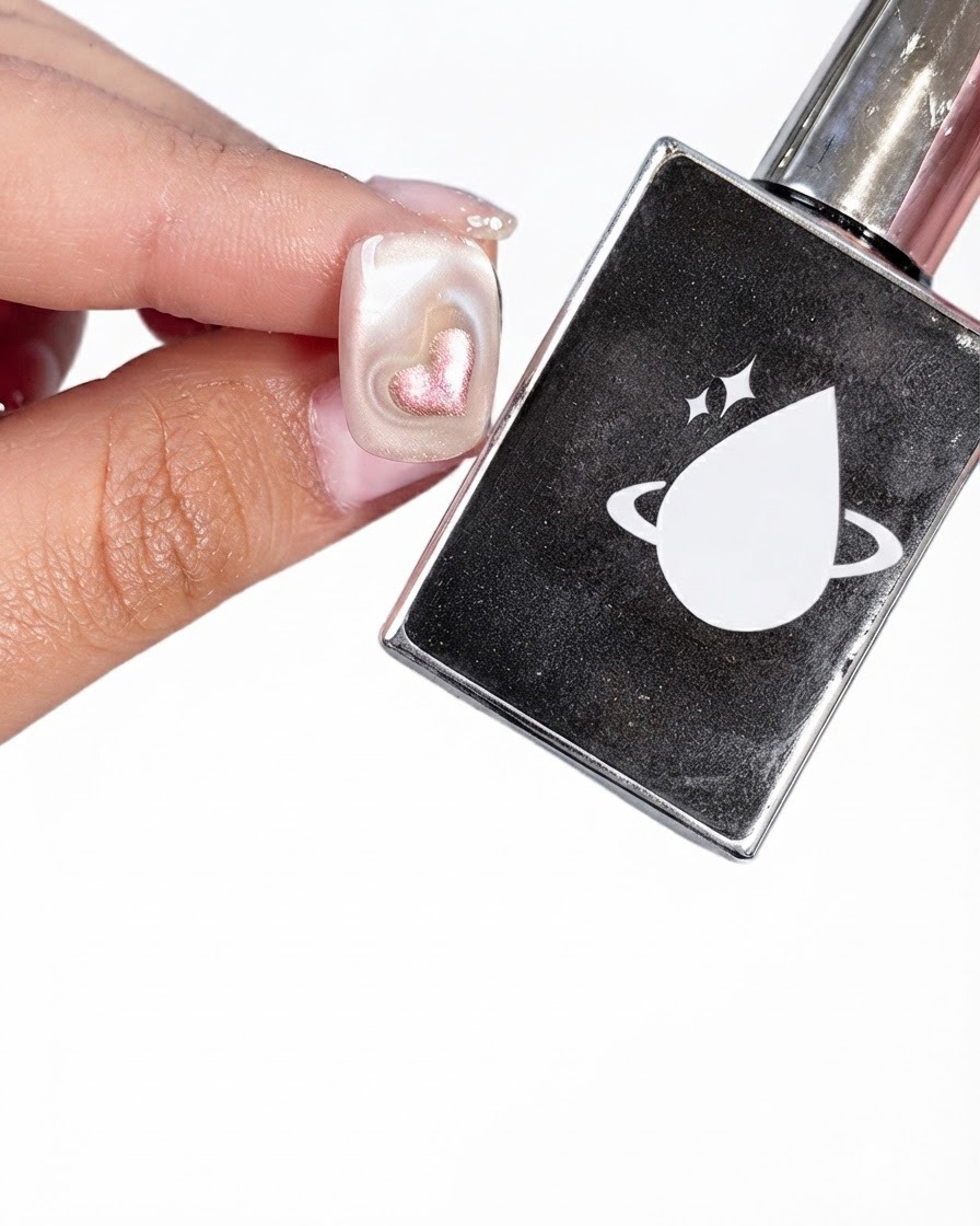A prepped nail held next to a black bottle of top coat featuring a white planet and drop logo.