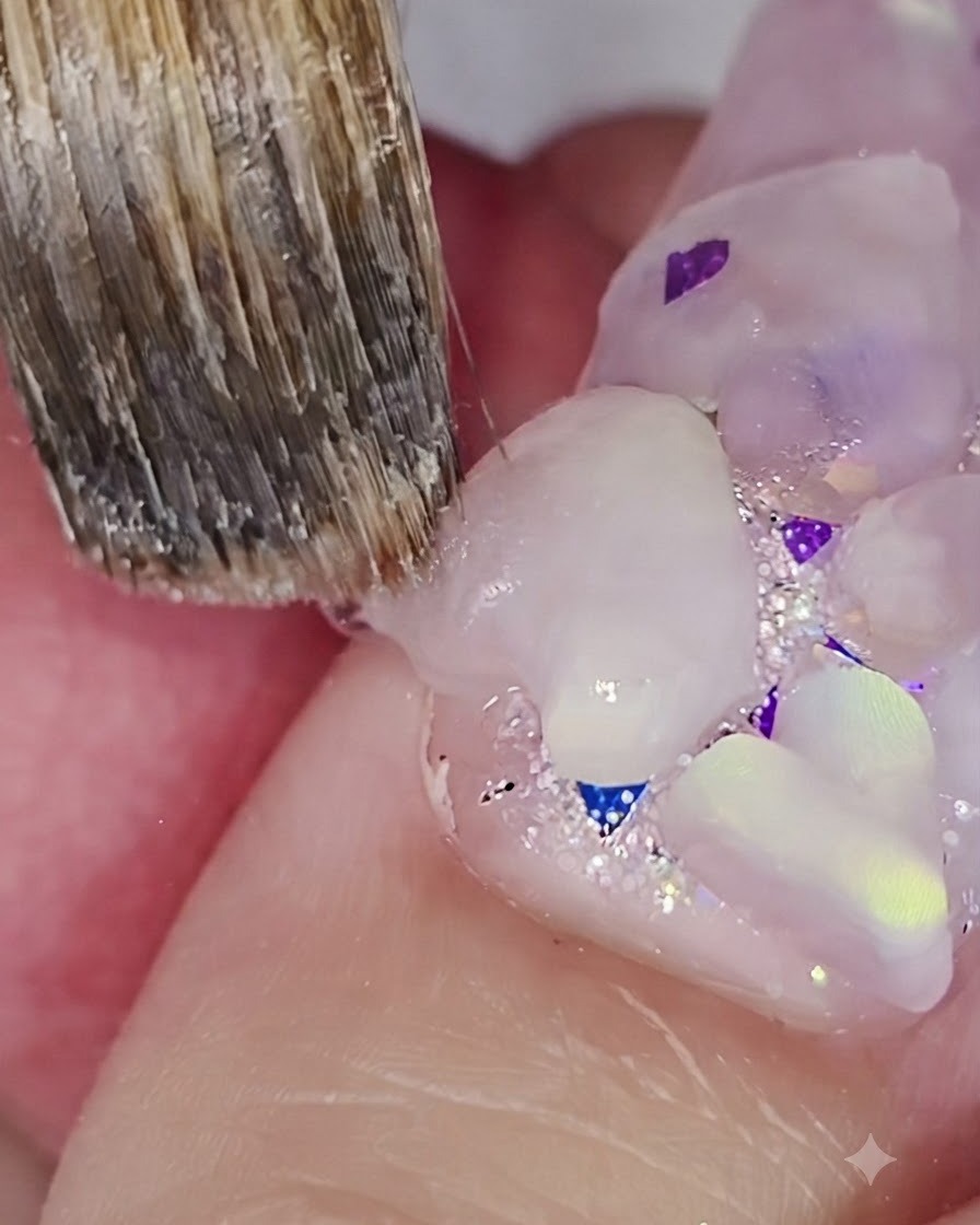 A nail brush detailing and sharpening the edges of a 3D acrylic heart on a nail.