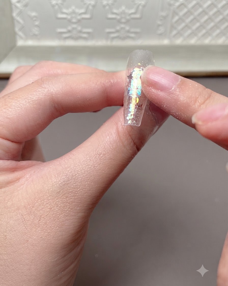 A finger lightly pressing or checking a cured nail extension surface after it has been under a UV or LED lamp.