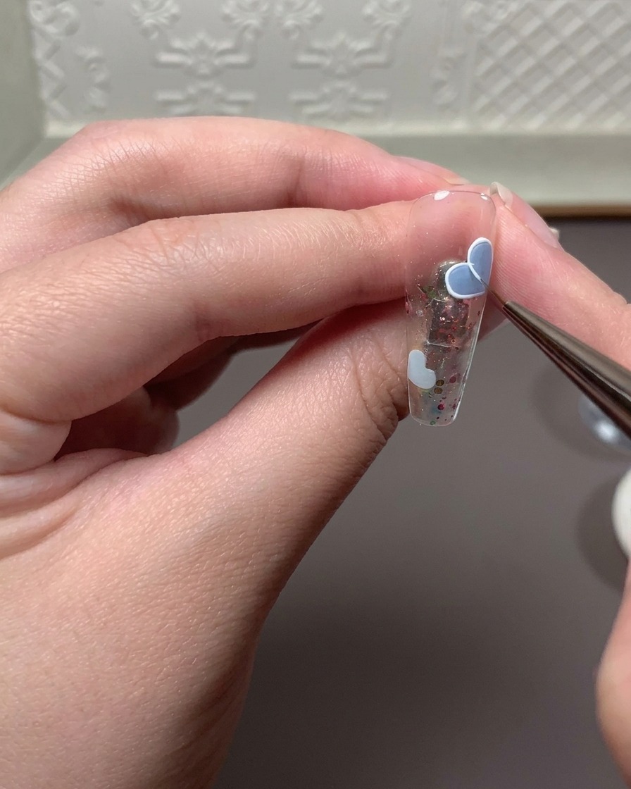 A fine brush applying a mixture of relief gel and white drawing gel to trace a heart outline.
