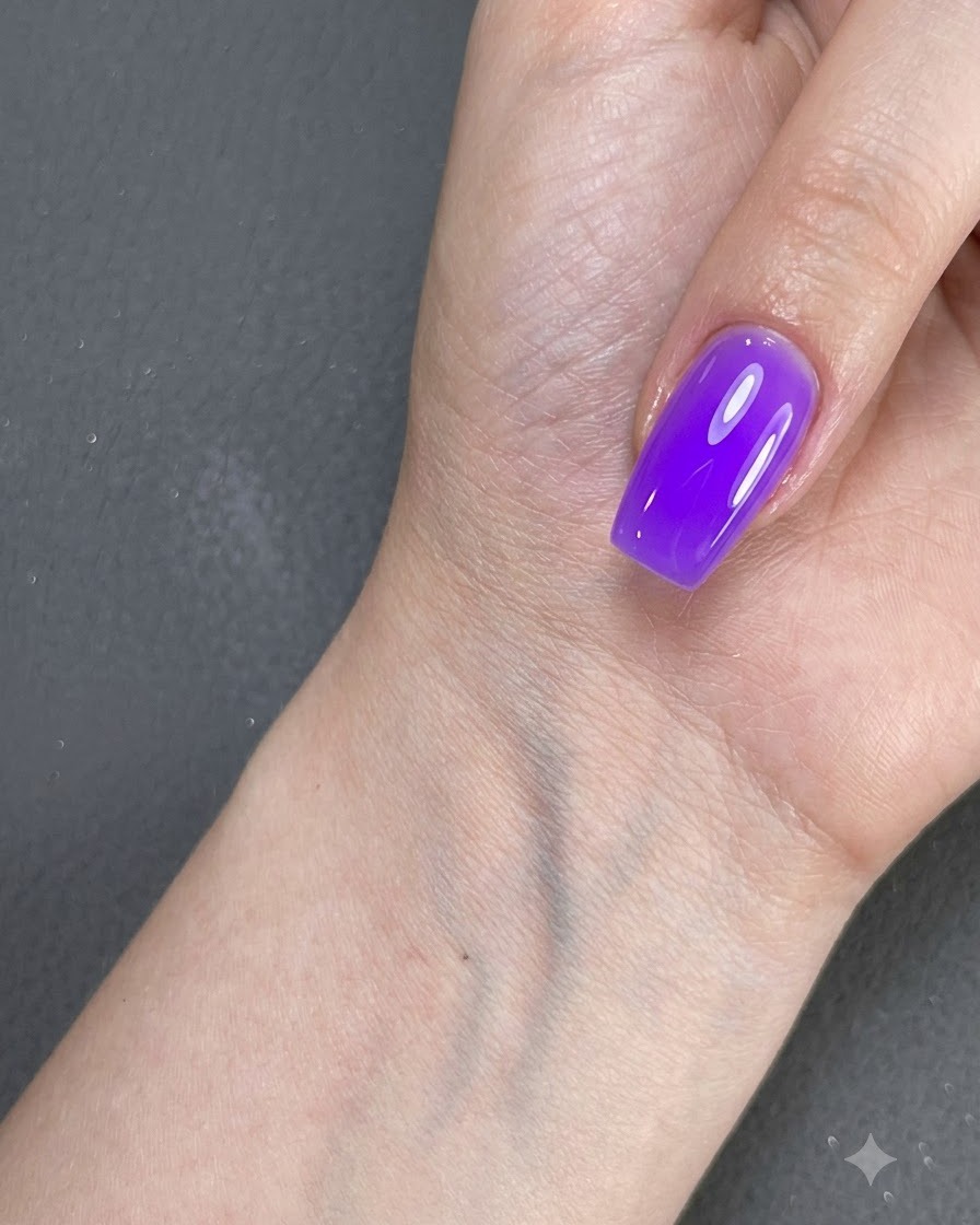 A hand with a purple polished nail resting near a surface under lighting.