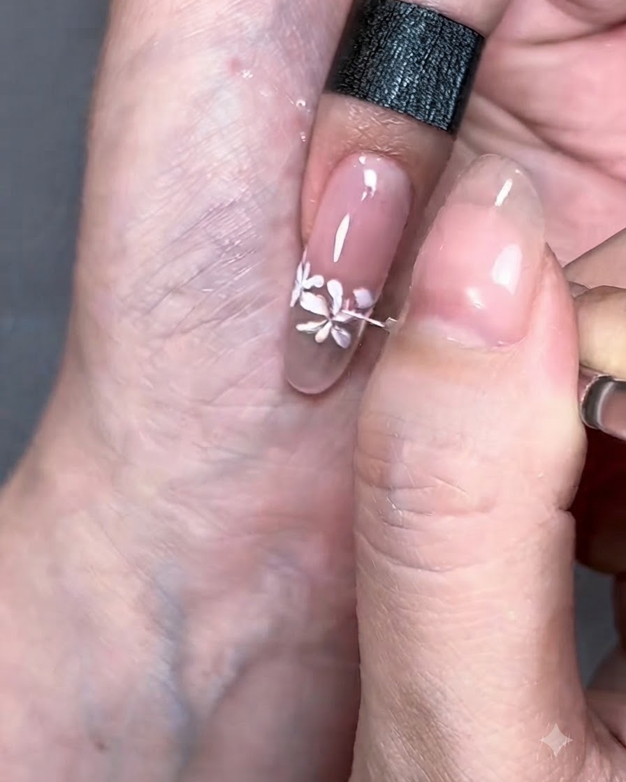 A fine liner brush drawing delicate white lines extending from the painted flowers.
