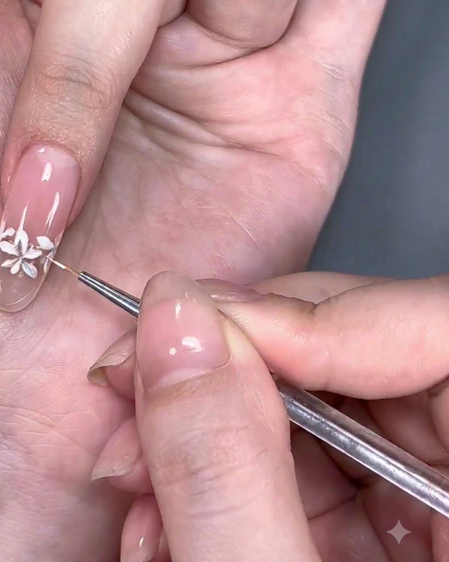 A close-up view of a fine brush adding tiny white dots to the flower centers.