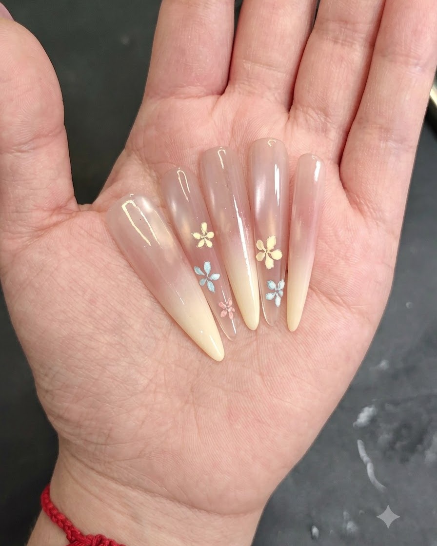 A close-up of a hand applying pink blush gel to the tip of an almond-shaped nail.