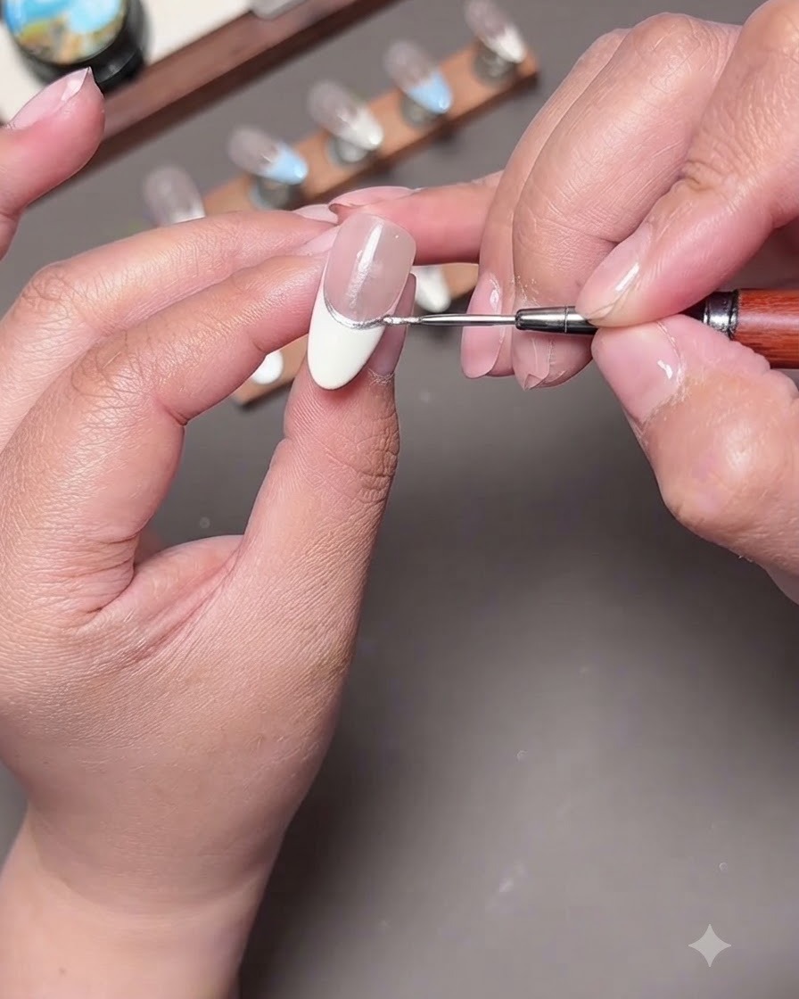 A close-up of a liner brush extending a light blue line down the nail surface.