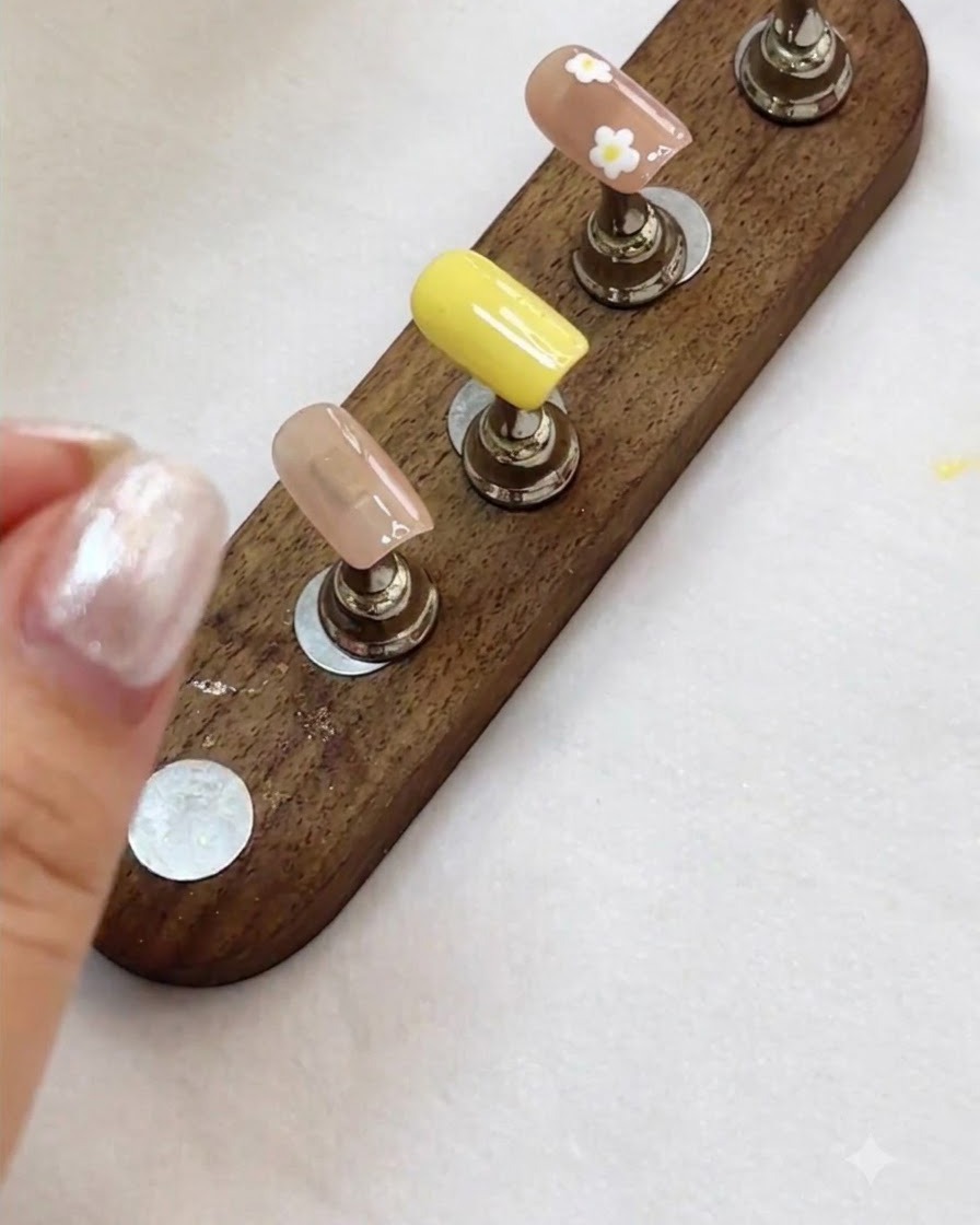 A nail display stand showing finished floral and nude nail art designs ready for the next step.