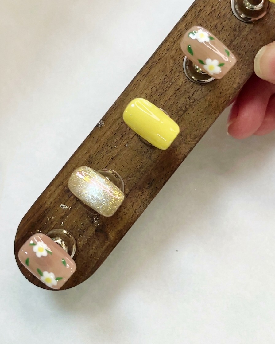 A wooden display stand holding custom-designed nail tips viewed from above.