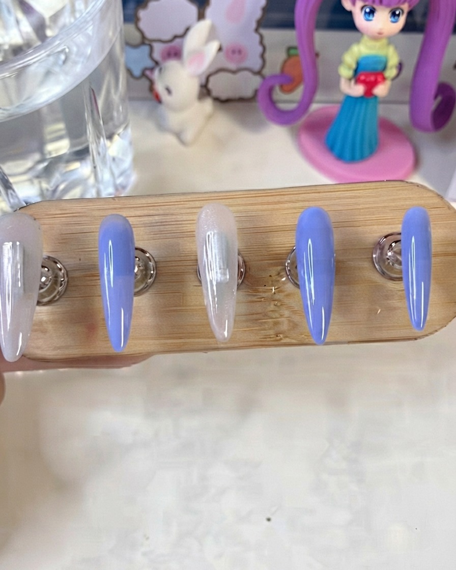 A nail stand showing blue and milky white painted nails curing under a UV/LED lamp.