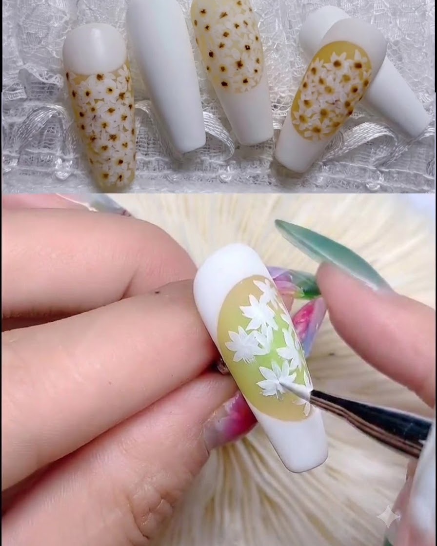 A fine brush applying light pink translucent dots to the center of the daisy petals.