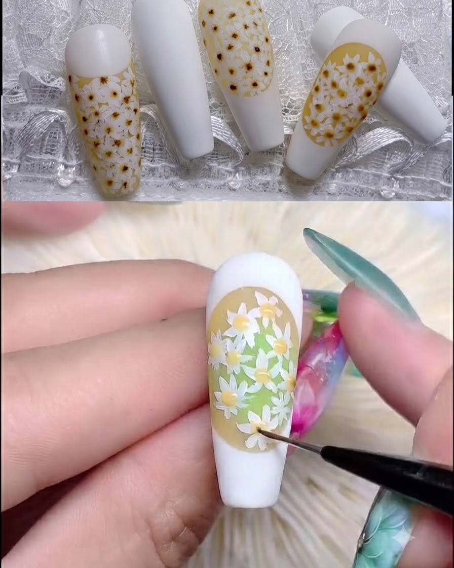 A nail brush applying clear rubber top coat over a textured daisy nail design.