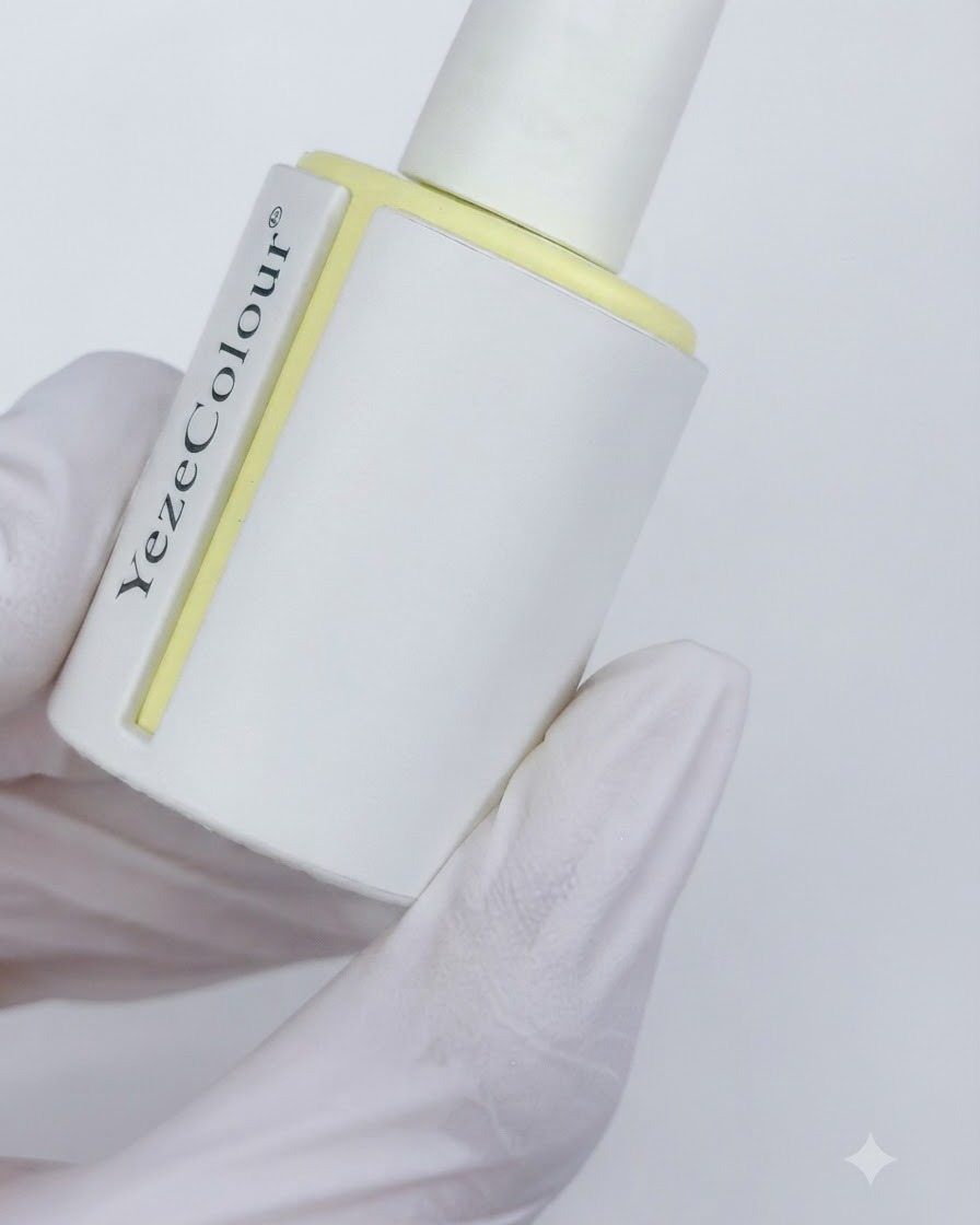 A bottle of velvet matte top coat labeled YezeColour held in a gloved hand.
