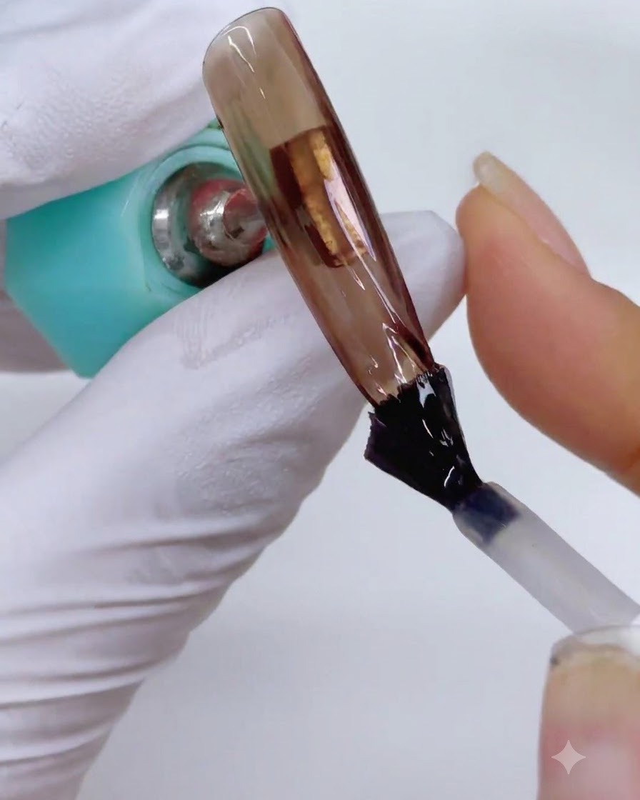 A nail extension being placed near a curing lamp to set the matte top coat layer.