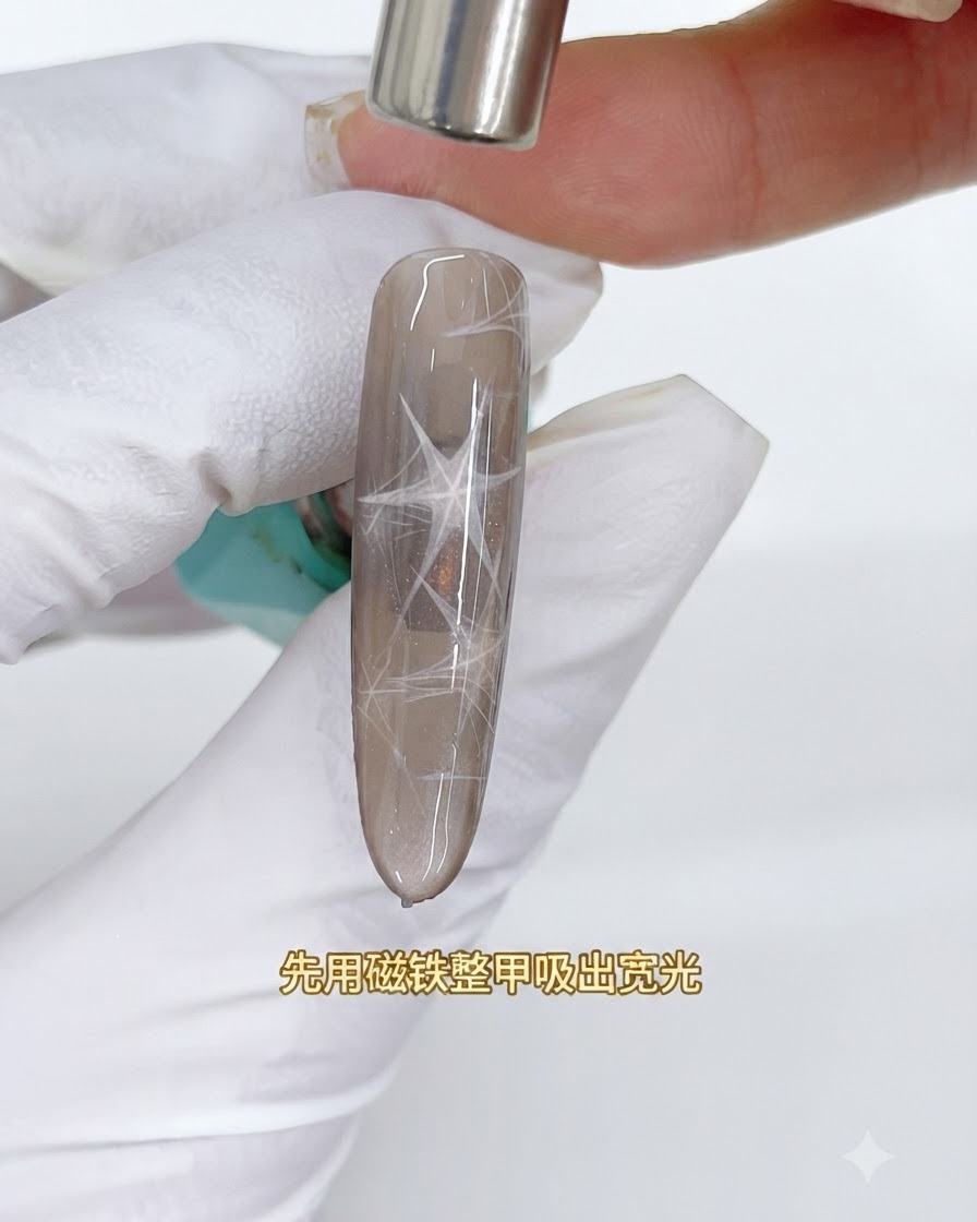 A cylindrical magnet hovering over a brown cat eye nail to draw out a wide reflective light band.