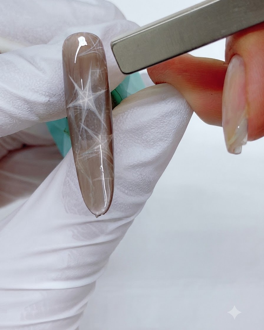 A rectangular bar magnet hovering over a brown nail to push the magnetic shimmer into a triangular pattern.
