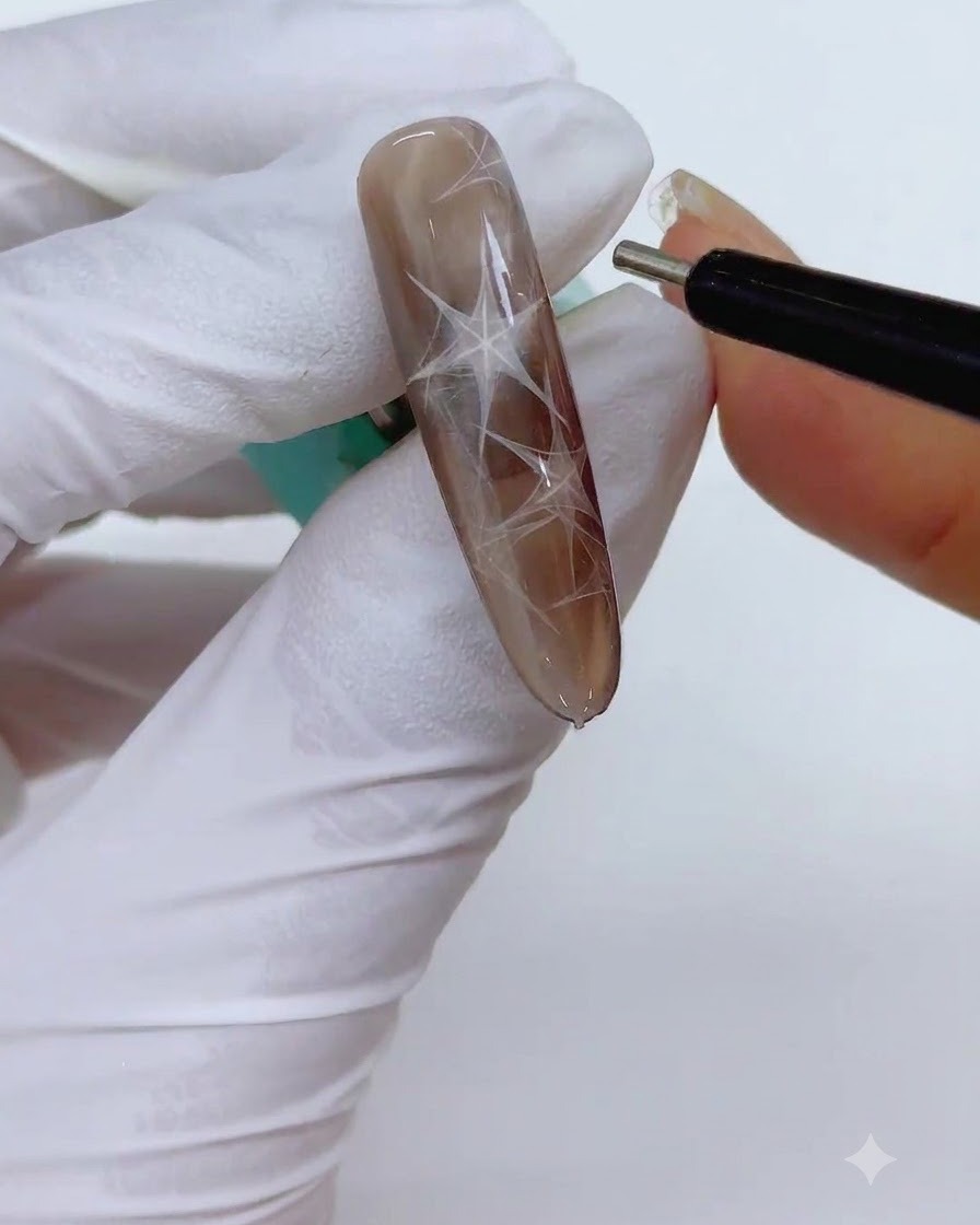 A fine cylindrical magnetic pen tool held near the nail to sharpen the edges of the magnetic triangular shape.