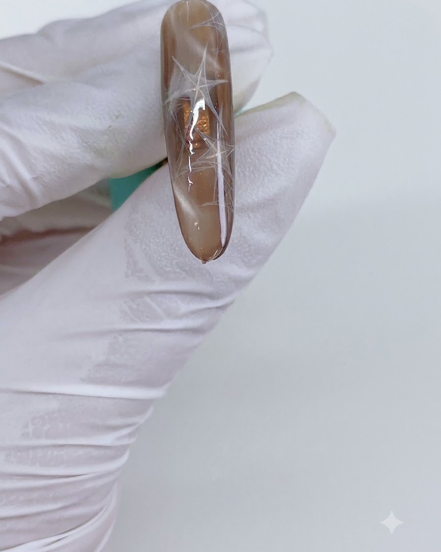 A manicured nail with cat eye triangles being placed under a curing light.