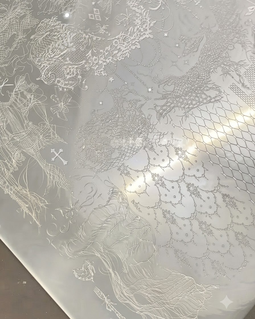 A clear stamper pressing onto a metal stamping plate filled with intricate white lace patterns.