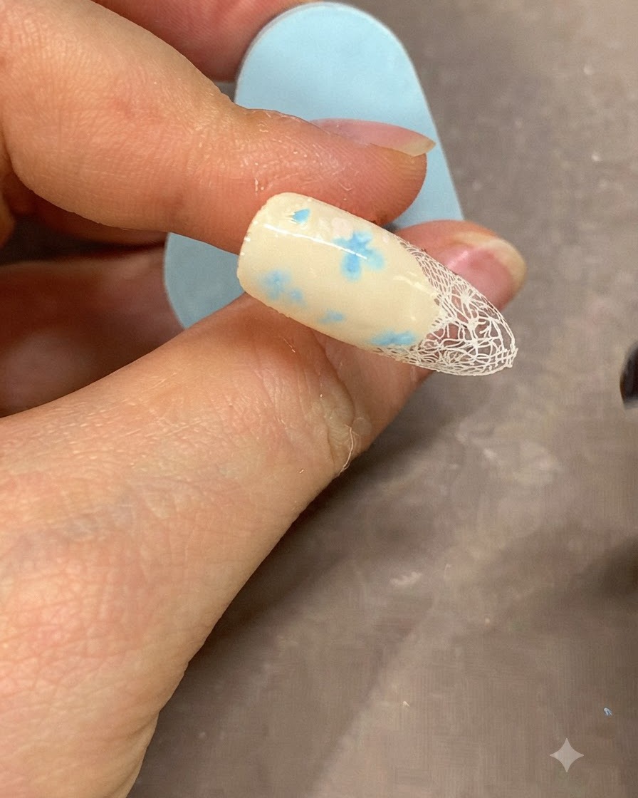 A fine brush applying a crisp white gel line along the edge of the French manicure.