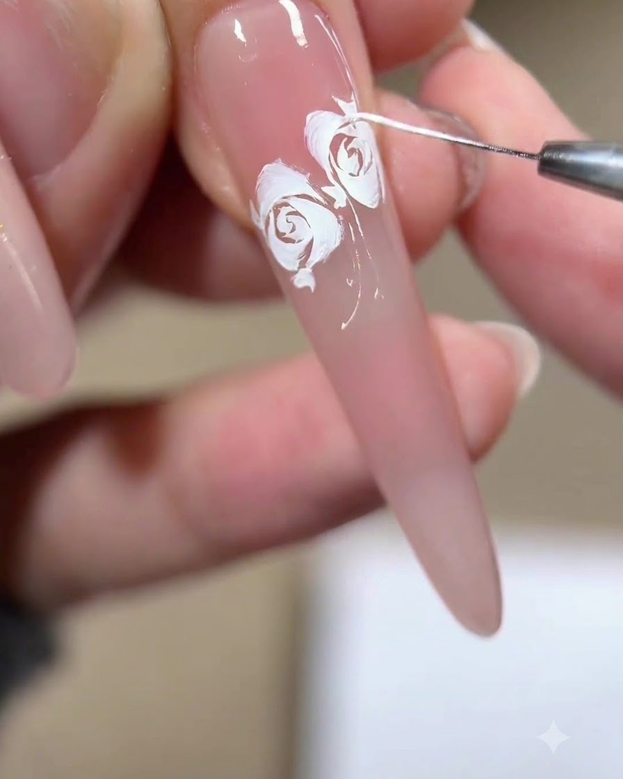 A close-up of a liner brush pulling fine white wisps and fragments around the edges of a completed rose design.
