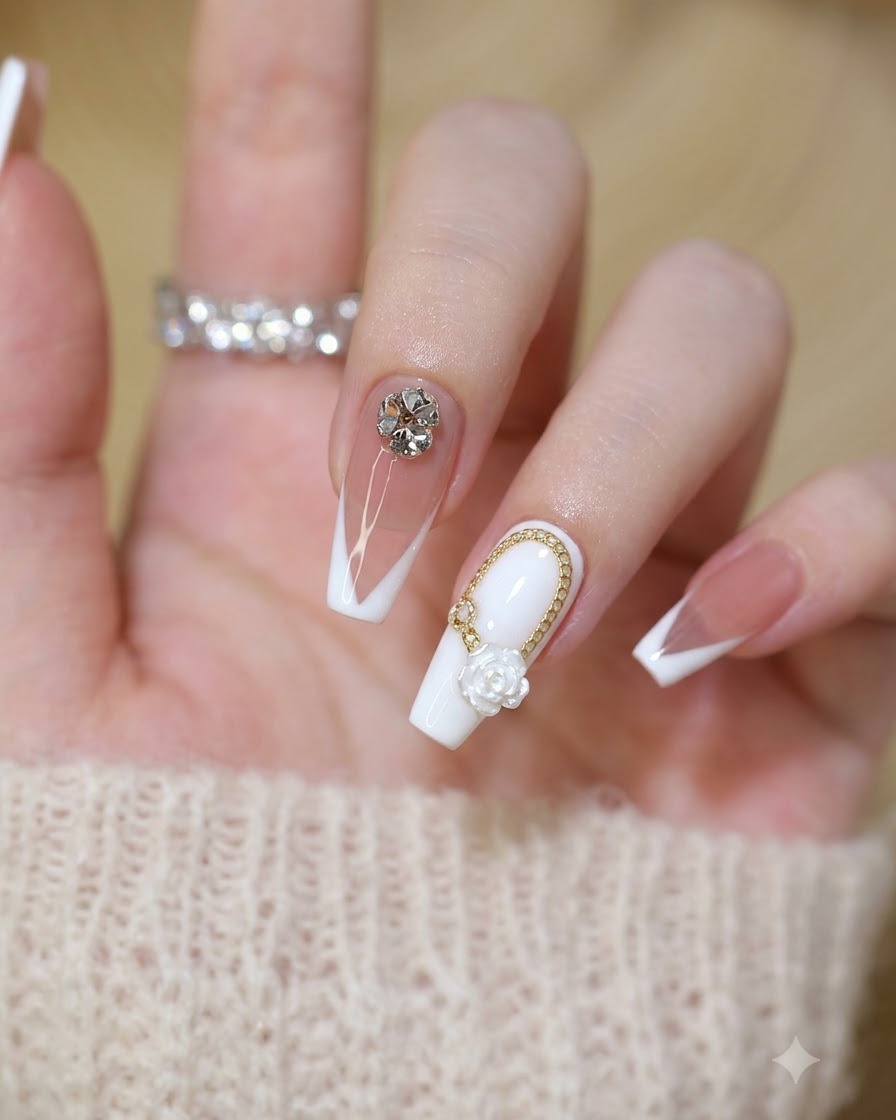 Close-up of a finished set of fairy-style nails featuring white roses, gold chains, and crystal rhinestones.