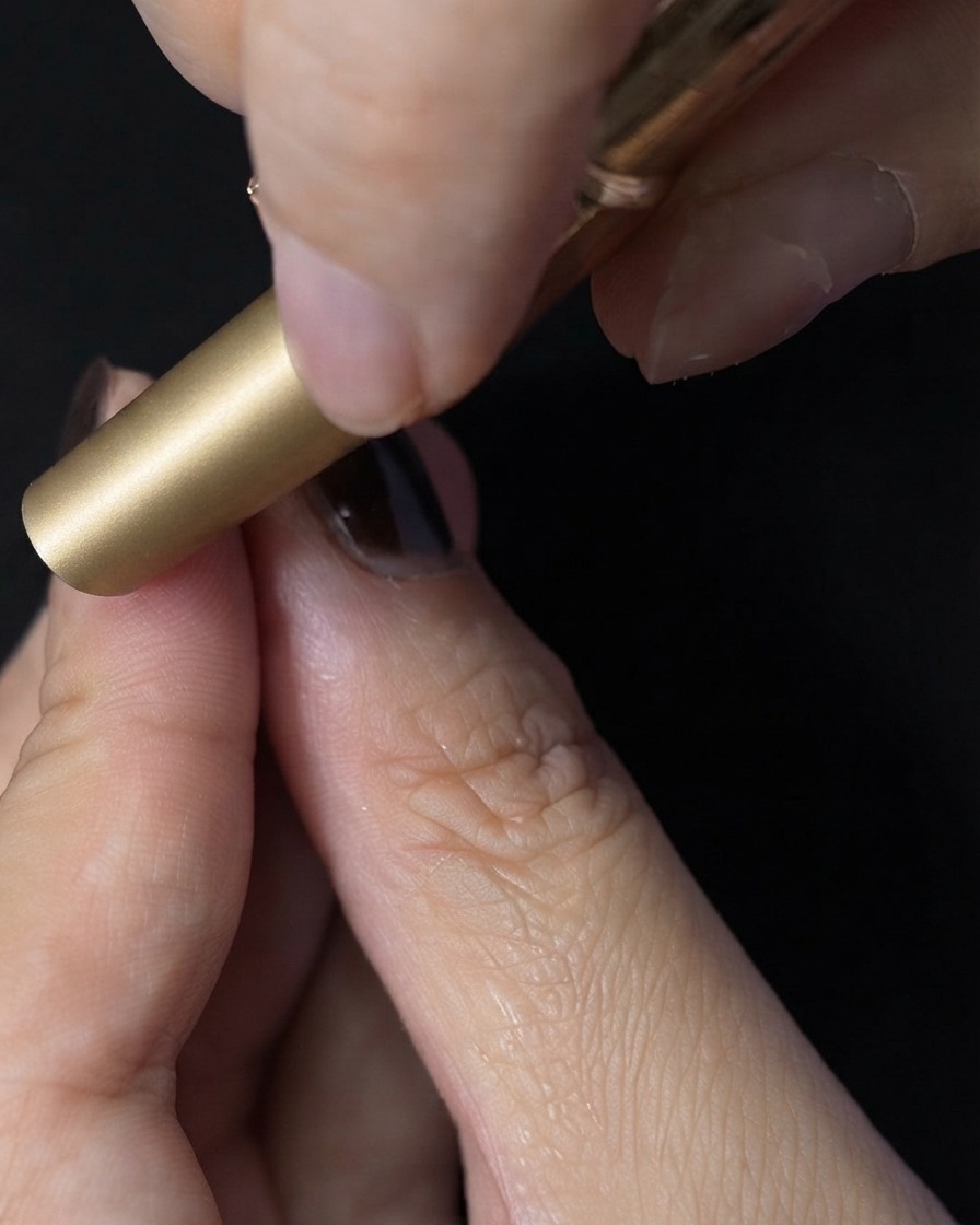 A fingernail placed inside a mini UV LED lamp for curing the top coat.