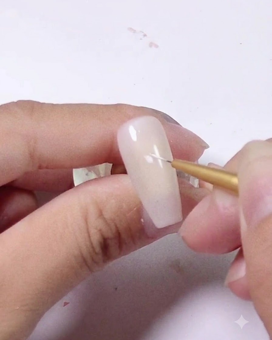 A close-up shot of a fine liner brush placing a tiny white stroke on a light pink nail.