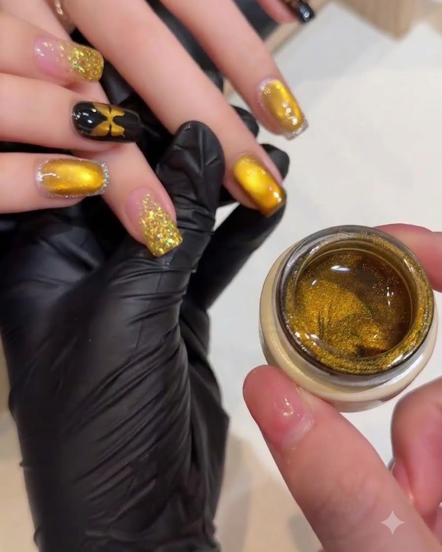 A manicurist using a small magnetic wand to shape the shimmering particles on a gold cat-eye nail.
