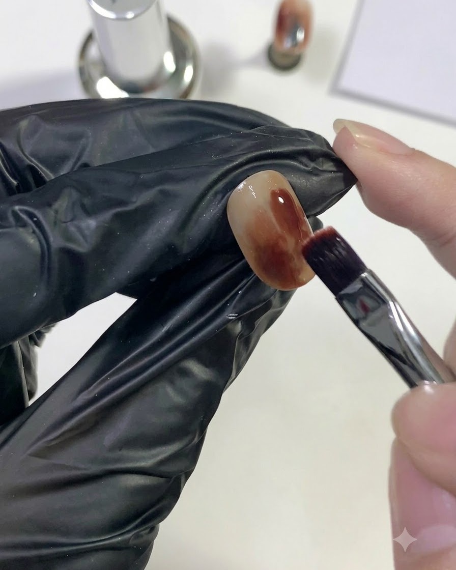 A brush applying deep red gel onto a localized area of the nail.